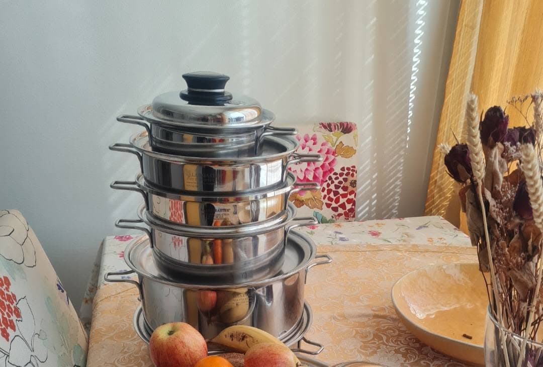 A stacked Saladmaster cookware set on a dining table